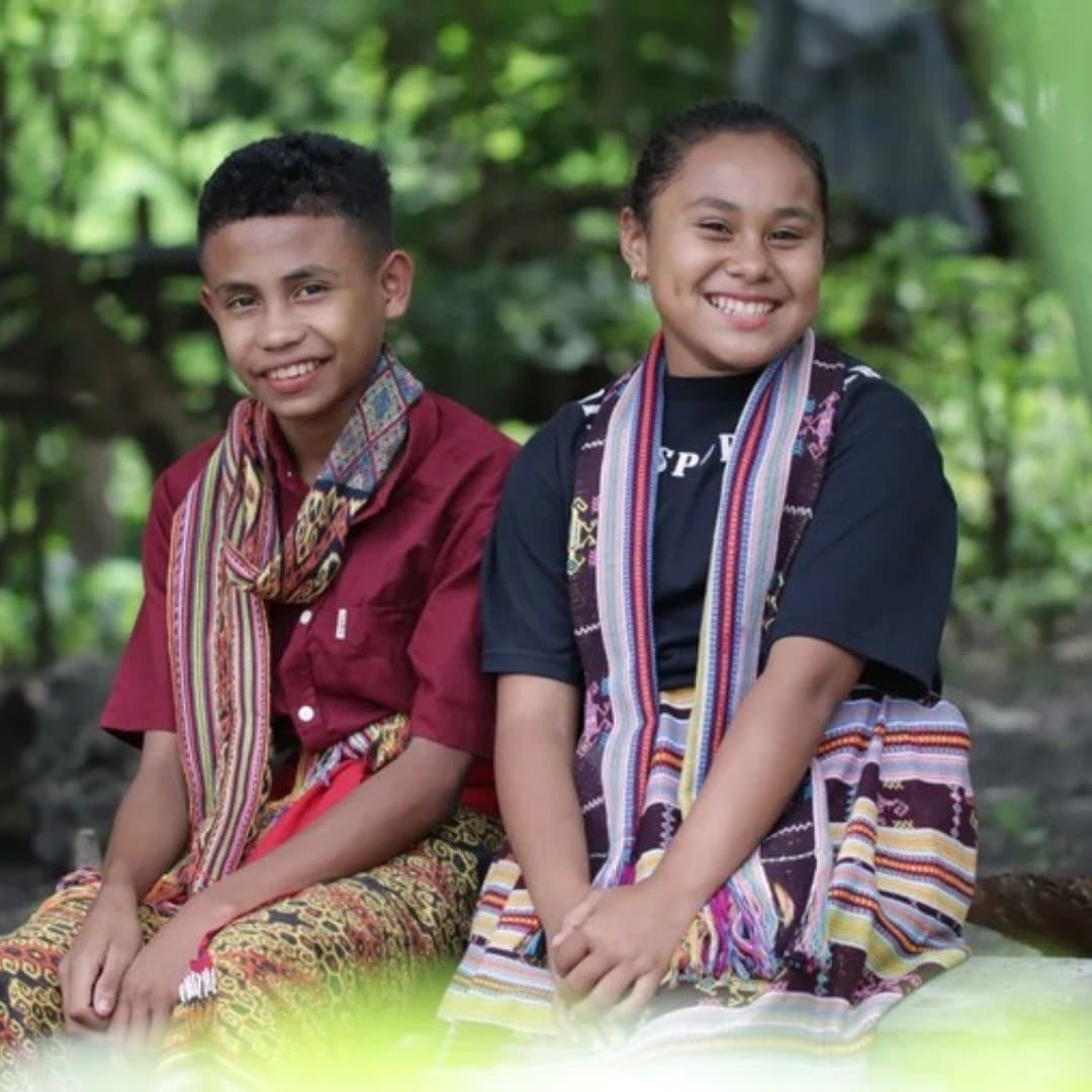 Two smiling students wearing traditional woven scarves